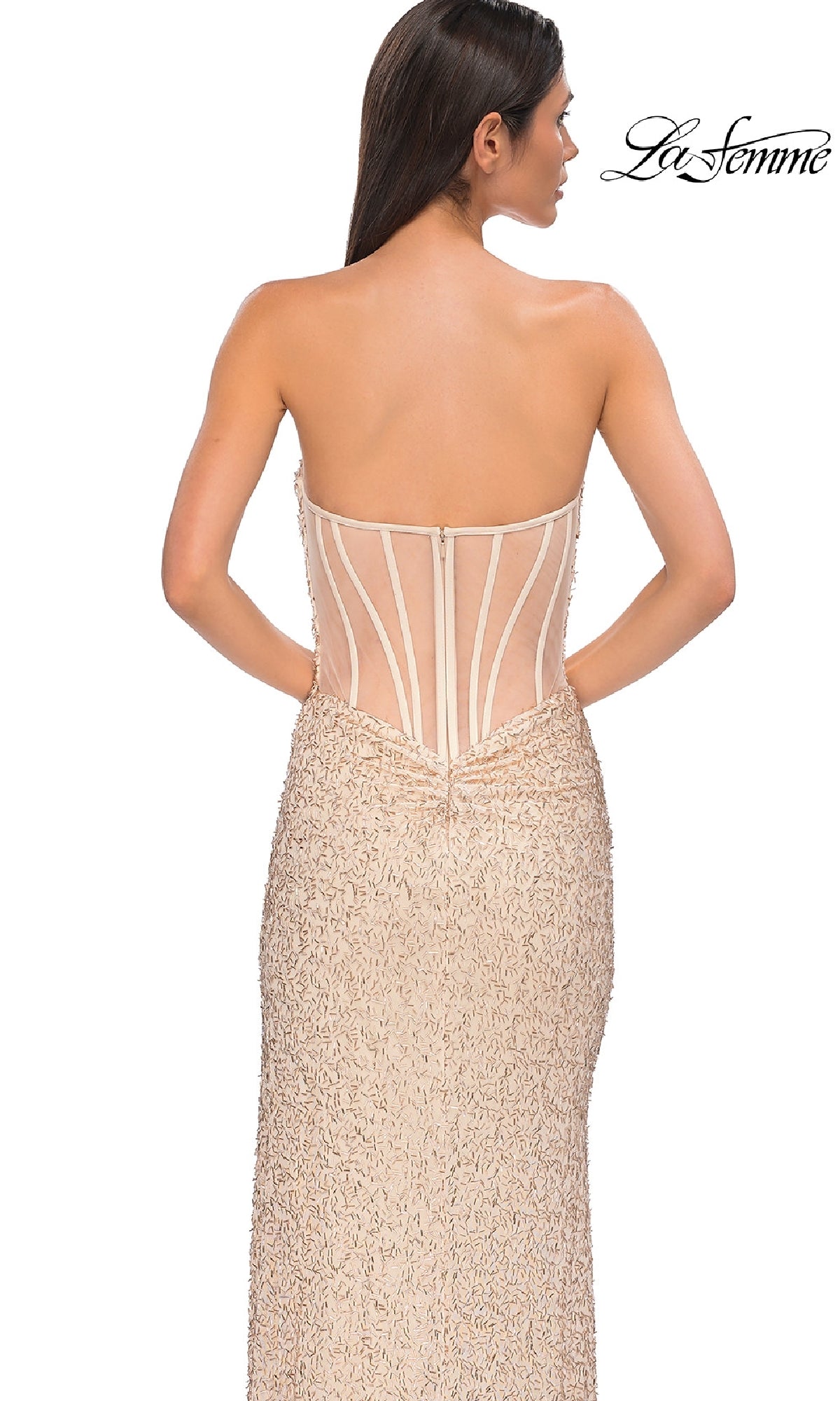 Woman wearing the Beaded Long Champagne Prom Dress: La Femme 32794, featuring a strapless beaded bodice, sheer corset back, and textured skirt, facing away from the camera.